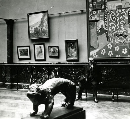 Photo d'archive d'Andry-Farcy assis dans les salles modernes du musée, devant le Fauve de Zadkine et les Aubergines de Matisse